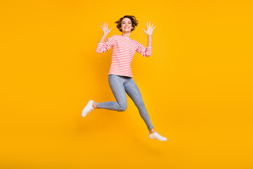 Full size photo of young beautiful happy smiling cheerful girl jumping showing hands isolated on yellow color background