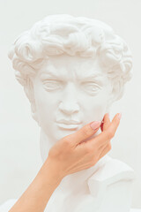 Women's hands gently touch the cheek of the plastic sculpture of a man.Creative concept.