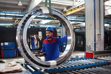 The worker controls the transport of the large diameter bearing. The control panel is in the hands...