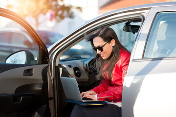 Fototapeta na wymiar Woman using her laptop from her car