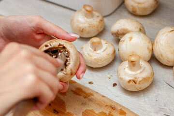Woman cooking fresh champignons on the kitchen table