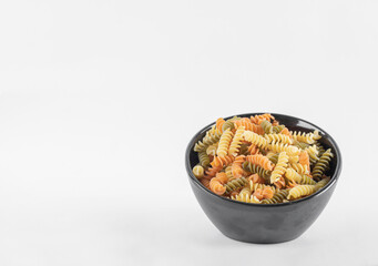 Raw colorful fusilli pasta in dark bowl