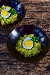 Mashed potato with peas and hard boiled egg garnish with parsley
