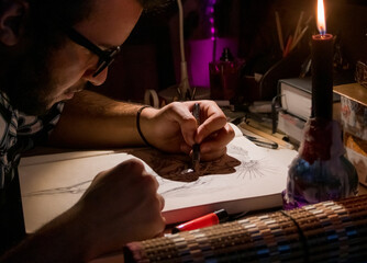 an artist and content creator recording a video for his channel in studio at home, focused on drawing under candle light