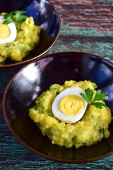 Mashed potato with peas and hard boiled egg garnish with parsley
