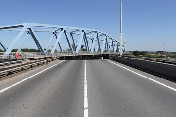 a swing bridge is turning with the road in front and a blue sky in summer in zeeland, the netherlands