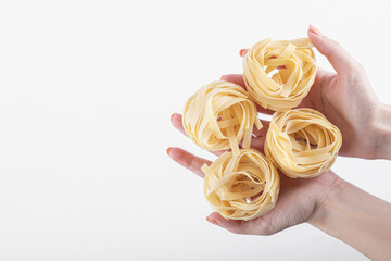 Female hands holding tagliatelle nests on white background