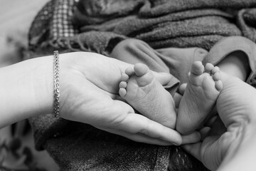 Cute little baby feet in mom's arms. Happy motherhood 