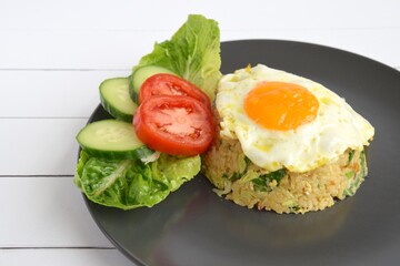 Nasi goreng or Indonesian fried rice with egg garnished with  lettuce, fresh cucumber slices , slice tomato and sunny side up 