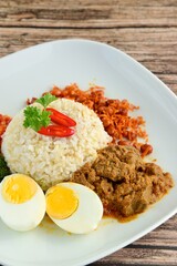 Indonesian cuisine Nasi Padang, rice with beef Rendang, salty anchovy peanut, boiled egg, crushed cassava leaves and Sambal