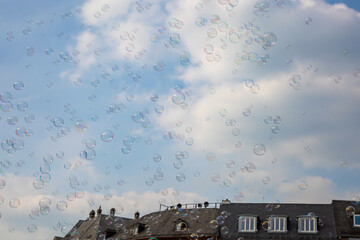 Bunte Seifenblasen fliegen an Häusern vorbei