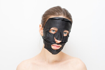 Young woman with purifying black mask on her face.