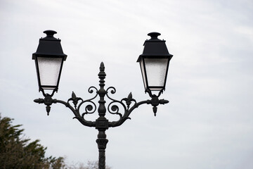 Fototapeta na wymiar Closeup of two vintage street lights on cloudy sky background