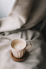 Cup of coffee with milk on beige plaid. Flat lay, top view still life morning breakfast. Comfort, cosiness and warmth concept. Photo in light pastel colors