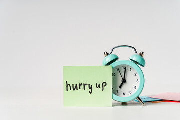 Alarm clock and sticker with the inscription HURRY UP on a white background. Planning and scheduling concept