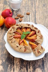 Galette with peaches and almond nuts garnish with mint verbena leaf. Selective focus