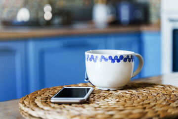 A mug of tea on the kitchen table, the blurry facade of the kitchen in the background. The concept of office or relaxation at home