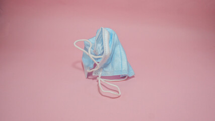 Crumpled Surgical COVID Face Mask on pink background