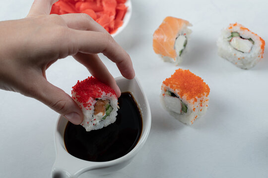 Dipping sushi roll into soya sauce and ginder