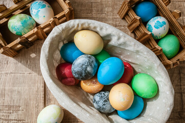 Basket with colored Easter eggs on brown wooden surface