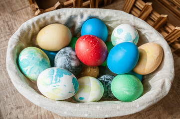 Basket with colored Easter eggs on brown wooden surface