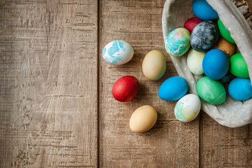 Basket with colored Easter eggs on brown wooden surface