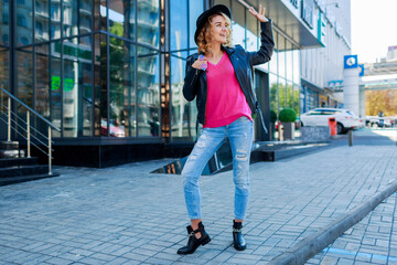 Blonde short haired woman walking  on streets of big modern city.  Fashionable urban outfit