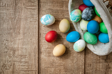 Basket with colored Easter eggs on brown wooden surface