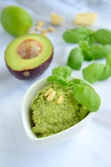 Basil avocado pesto sauce with main ingredients: fresh basil leaves, avocado, parmesan cheese, pine nuts, garlic and lime