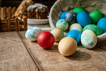 Fototapeta na wymiar Basket with colored Easter eggs and Easter cake lie on a brown wooden surface