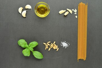 Italian cooking with whole wheat pasta and pesto ingredients; basil, garlic, olive oil, pine nuts,...