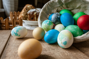 Obraz na płótnie Canvas Basket with colored Easter eggs and Easter cake lie on a brown wooden surface