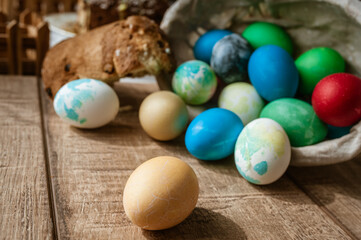 Basket with colored Easter eggs and Easter cake lie on a brown wooden surface