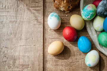 Basket with colored Easter eggs and Easter cake lie on a brown wooden surface