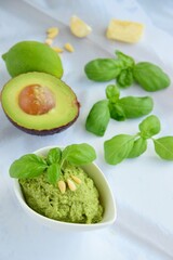 Basil avocado pesto sauce with main ingredients: fresh basil leaves, avocado, parmesan cheese, pine nuts, garlic and lime