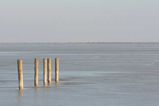 wooden pile in a frozen lake mith space for text