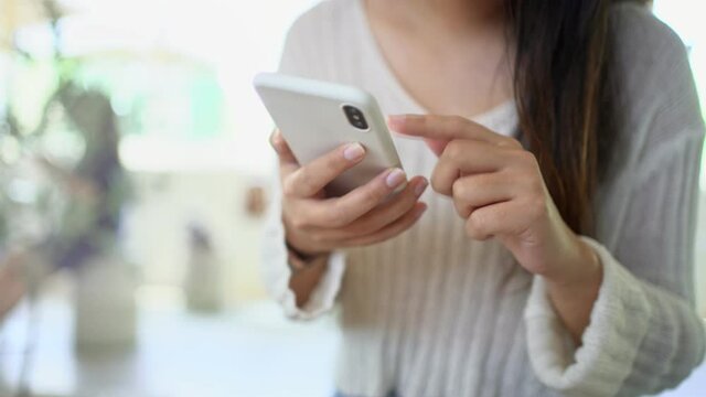 Young asian woman using smart phone at cafe, selective focus.
