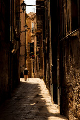 in the historic center of Palermo an elderly person with a cane returns home for lunch 