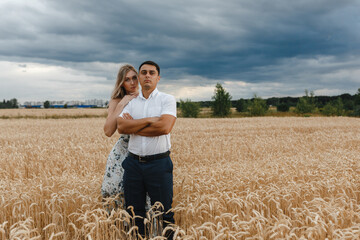 Naklejka na ściany i meble Love story of a young beautiful couple in beautiful wheat field.