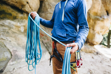Close-up of a strong climber with equipment on a belt holding rope and preparing to climb