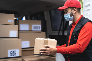 Delivery man wearing face protective mask to avoid corona virus spread - Young express courier working during coronavirus outbreak - Deliver and online buying concept - obrazy, fototapety, plakaty