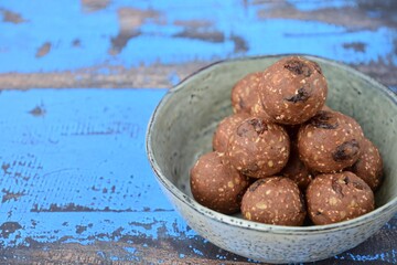 Homemade healthy energy balls with chocolate, raisin, quinoa and oat on blue background
