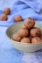Homemade healthy energy balls with chocolate, raisin, quinoa and oat on blue background

