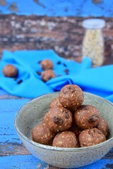 Homemade healthy energy balls with chocolate, raisin, quinoa and oat on blue background
