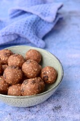 Homemade healthy energy balls with chocolate, raisin, quinoa and oat on blue background
