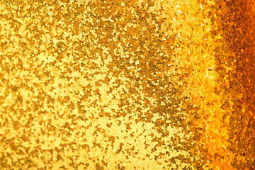 Shiny gold sequins background, bokeh sequins texture. Beautiful festive Christmas background for the design of congratulations. Sparkling pearl yellow texture. Gold surface with patterns.