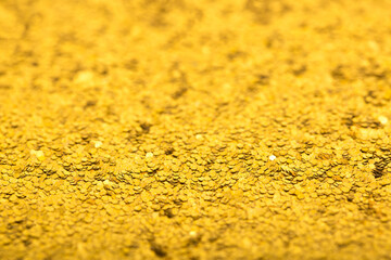 Shiny gold sequins background, bokeh sequins texture. Beautiful festive Christmas background for the design of congratulations. Sparkling pearl yellow texture. Gold surface with patterns.