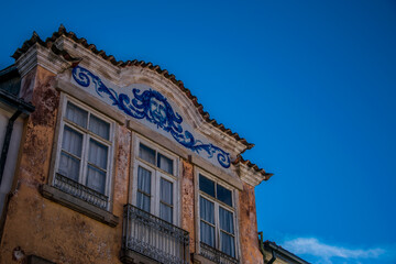 Remate superior en el frontal de una casa de la ciudad de Bragança, Portugal, con trabajo de azulejos figurativos en tonos azules.