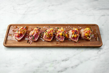 Japanese classic dish - tataki tuna with unagi sauce, hot pepper, served in a wooden board on a...