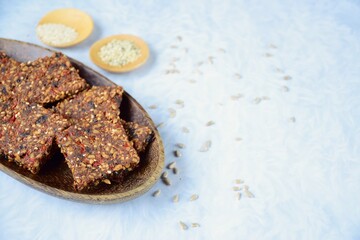 Seed crackers made from bell pepper, sun dried tomato, sunflower seed, sesame seed, hemp seed and flax seeds. Text space, white background